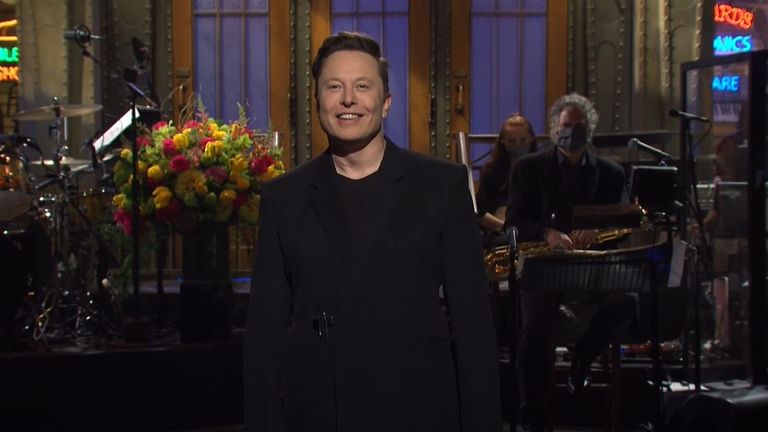 Elon Musk uśmiecha się, gdy publiczność śmieje się z jego żartów, gdy prowadzi Saturday Night Live.  Zdjęcie: NBC/YouTube