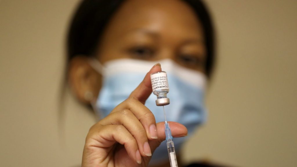 A health worker holds a vial of the Pfizer/BioNTech COVID vaccine at a care centre outside Johannesburg