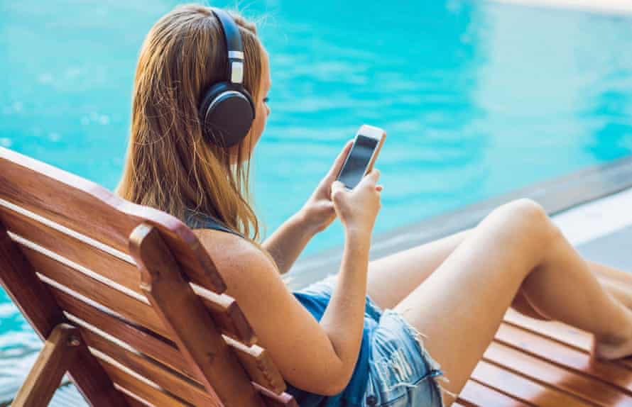 Ktoś używa telefonu komórkowego do odtwarzania piosenek, relaksując się ze słuchawkami podczas letnich wakacji