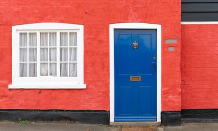 Kolorowy domek w brytyjskiej wiosce z czerwonymi ścianami i niebieskimi drzwiami.